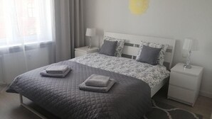 Quarto com cama, duas mesas de cabeceira e uma janela com cortinas.
