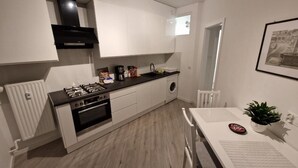 Cozinha moderna com armários brancos, fogão preto e uma pia.