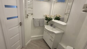 Casa de banho com lavatório branco, espelho e porta-toalhas.