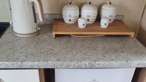 Eine Küche mit einer Granitabdeckung, einer Kaffeemaschine und drei Behältern, beschriftet mit Tee, Kaffee und Zucker.