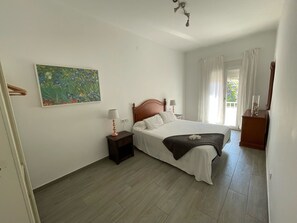 A bedroom with a bed, nightstands, a painting, and a window with curtains. - Budha's apartment, relax & confort center Calafell (Calafell)
