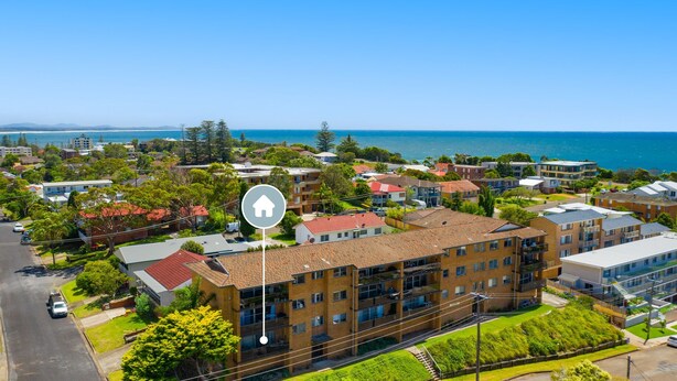 Un quartier résidentiel composé d’immeubles de différentes hauteurs, offrant une vue dégagée sur la mer et donnant sur une rue importante.