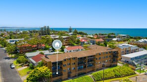 Un quartier résidentiel composé d’immeubles de différentes hauteurs, offrant une vue dégagée sur la mer et donnant sur une rue importante.