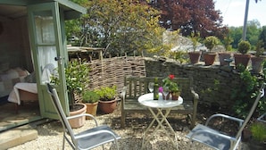 A patio with two metal chairs, a small round table, and potted plants. - Chapel Cottage, spacious light and airy cottage in the Cotswolds AONB (Cirencester)