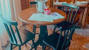 Una mesa de madera para comer con cuatro sillas, una botella de champán y un menú sobre la mesa.
