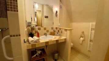 A bathroom with a sink, mirror, towel rack, and a small table with a hairdryer.