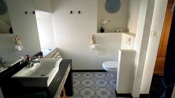 Een badkamer met een grote spiegel, een wastafel, een toilet en een douche.