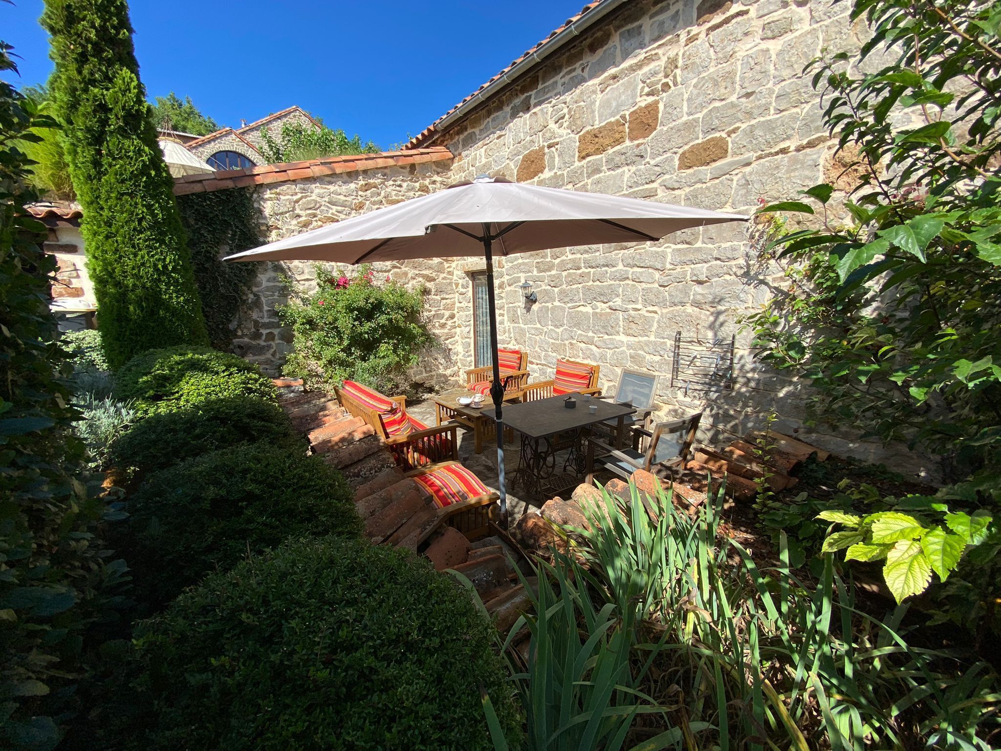 A stone building with a patio area featuring a table and chairs under a large umbrella.