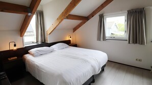 A bedroom with a bed, nightstands, a window with curtains, and exposed wooden beams. - Bungalow by Water With Sauna in South Holland (Simonshaven)