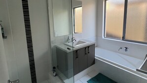 Une salle de bain moderne avec une douche à parois de verre, un grand miroir, un lavabo et une baignoire.