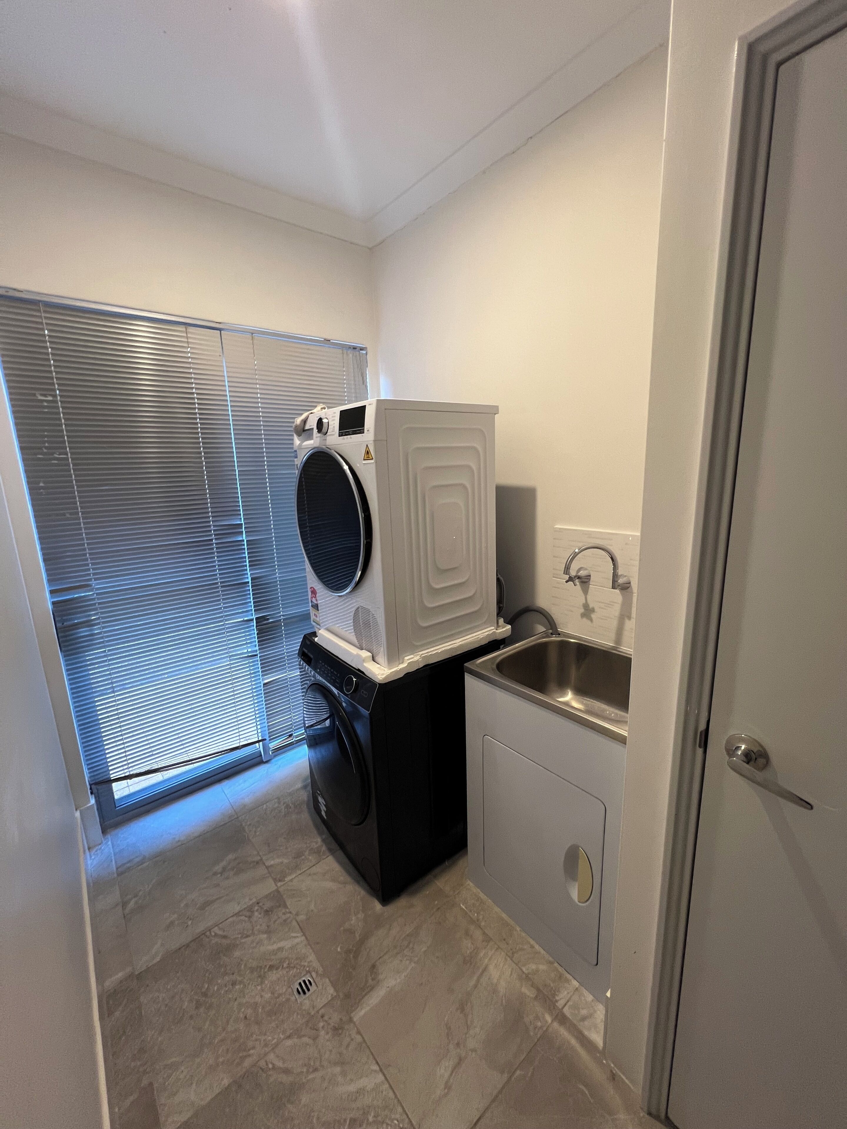 A compact laundry room with a washing machine, dryer, and sink.