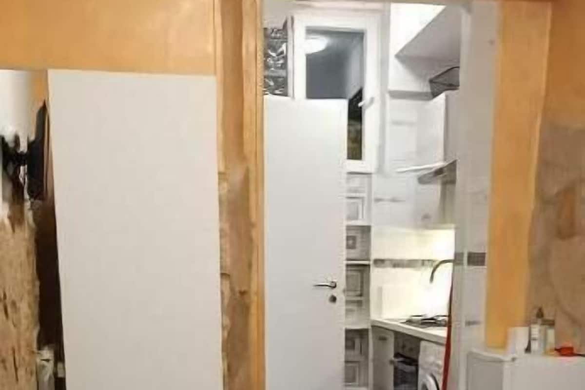 Un pasillo estrecho que conduce a una zona de cocina con lavadora y una mesa.