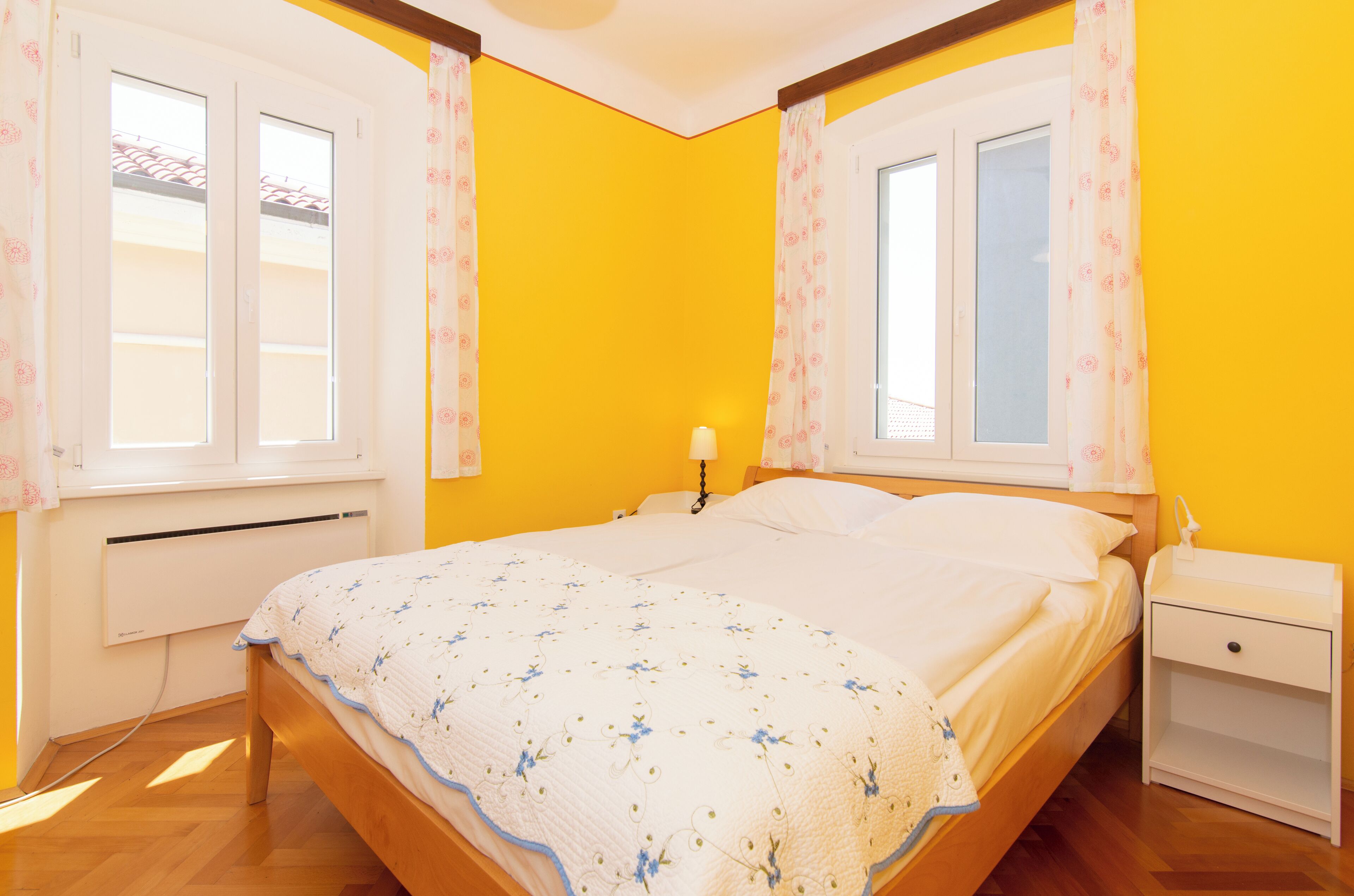 Ein Schlafzimmer mit Bett, Nachttisch und einem Fenster mit Vorhängen.