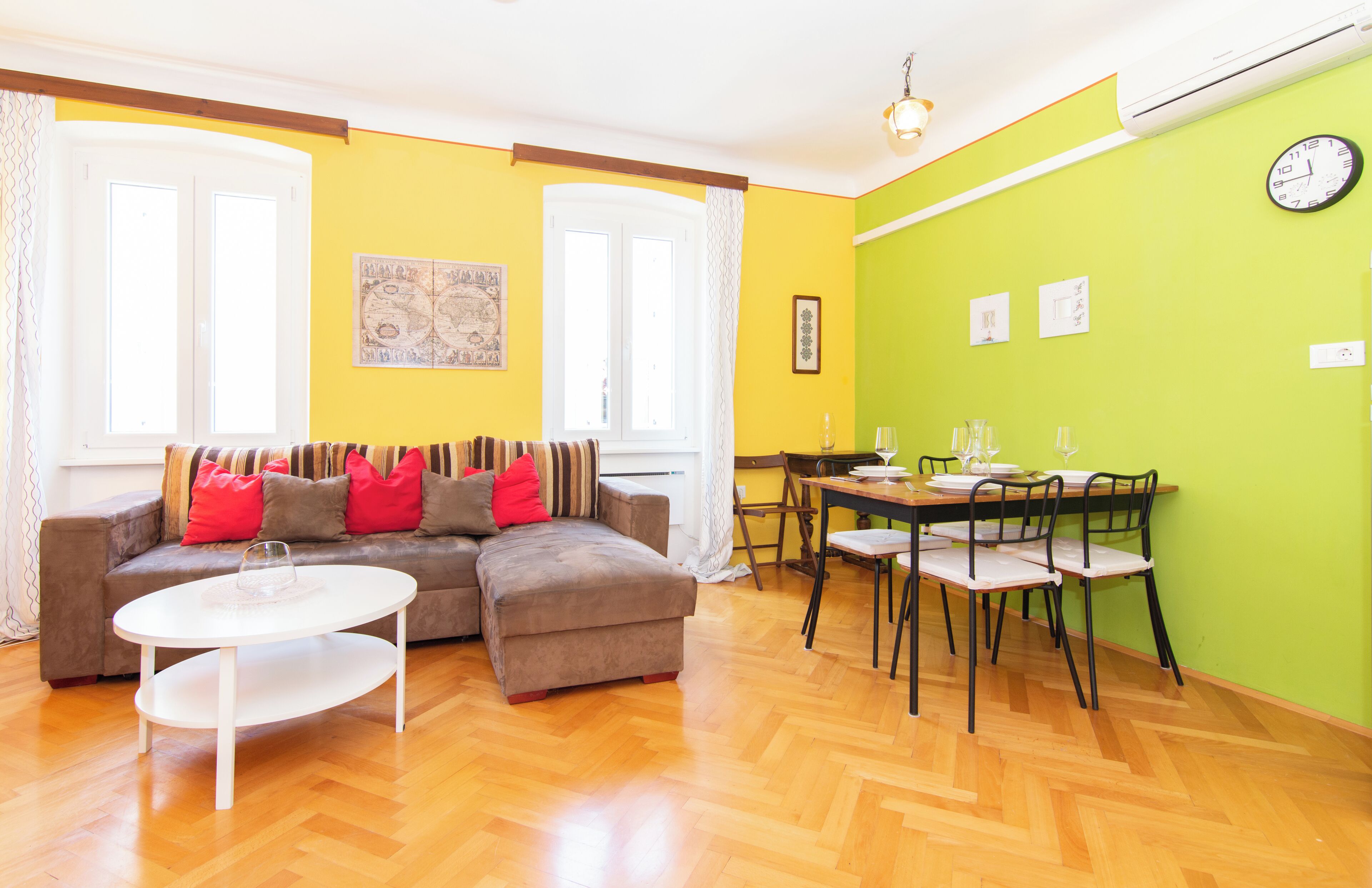 A living room with a sofa, a coffee table, and a dining table with chairs.