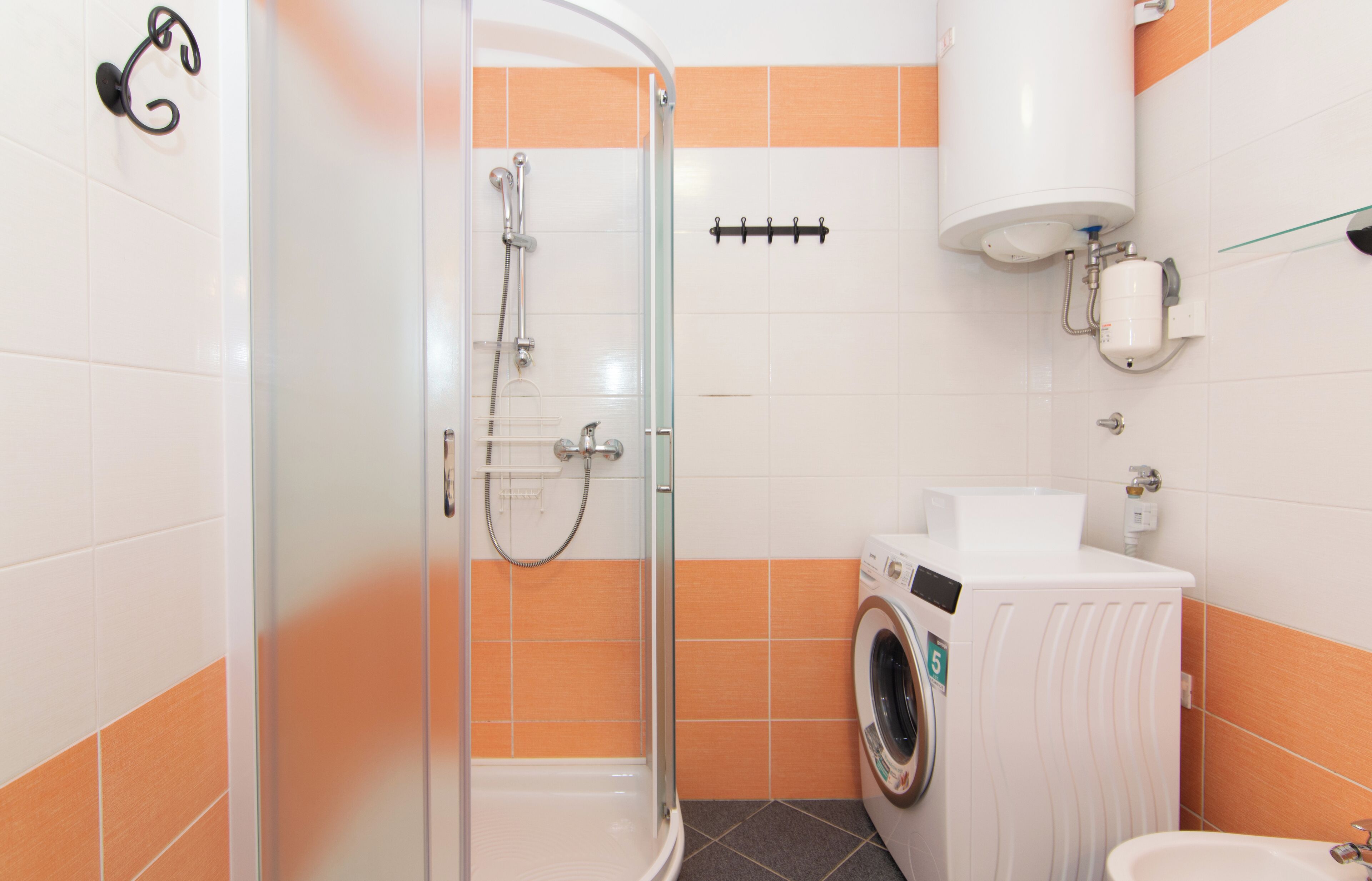 A bathroom with a glass-enclosed shower, a washing machine, and a toilet.