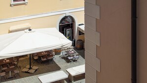 An outdoor patio area with tables and chairs, a large umbrella, and a building entrance.