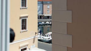 A view of a marina with boats docked, buildings with balconies, and a clear sky.
