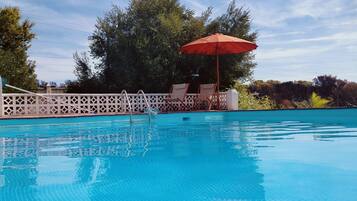 Una piscina amb una superfície d'aigua blava i cristal·lina, envoltada d'una tanca blanca amb disseny de reixeta.