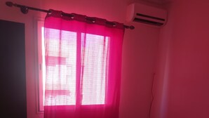 A bedroom with a bed, a window with pink curtains, and an air conditioning unit. - Nice apartment in marakech, for a good stay  (Marakech)