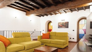 Un salon spacieux avec deux canapés jaunes, une table basse en bois et un téléviseur posé sur un meuble en bois.
