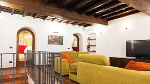 Un salon avec un canapé jaune, un téléviseur et un escalier doté d’une rampe.