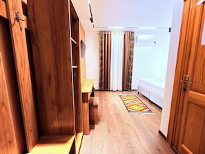 Une pièce comprenant une armoire en bois, un lit, un bureau et un tapis à motifs.