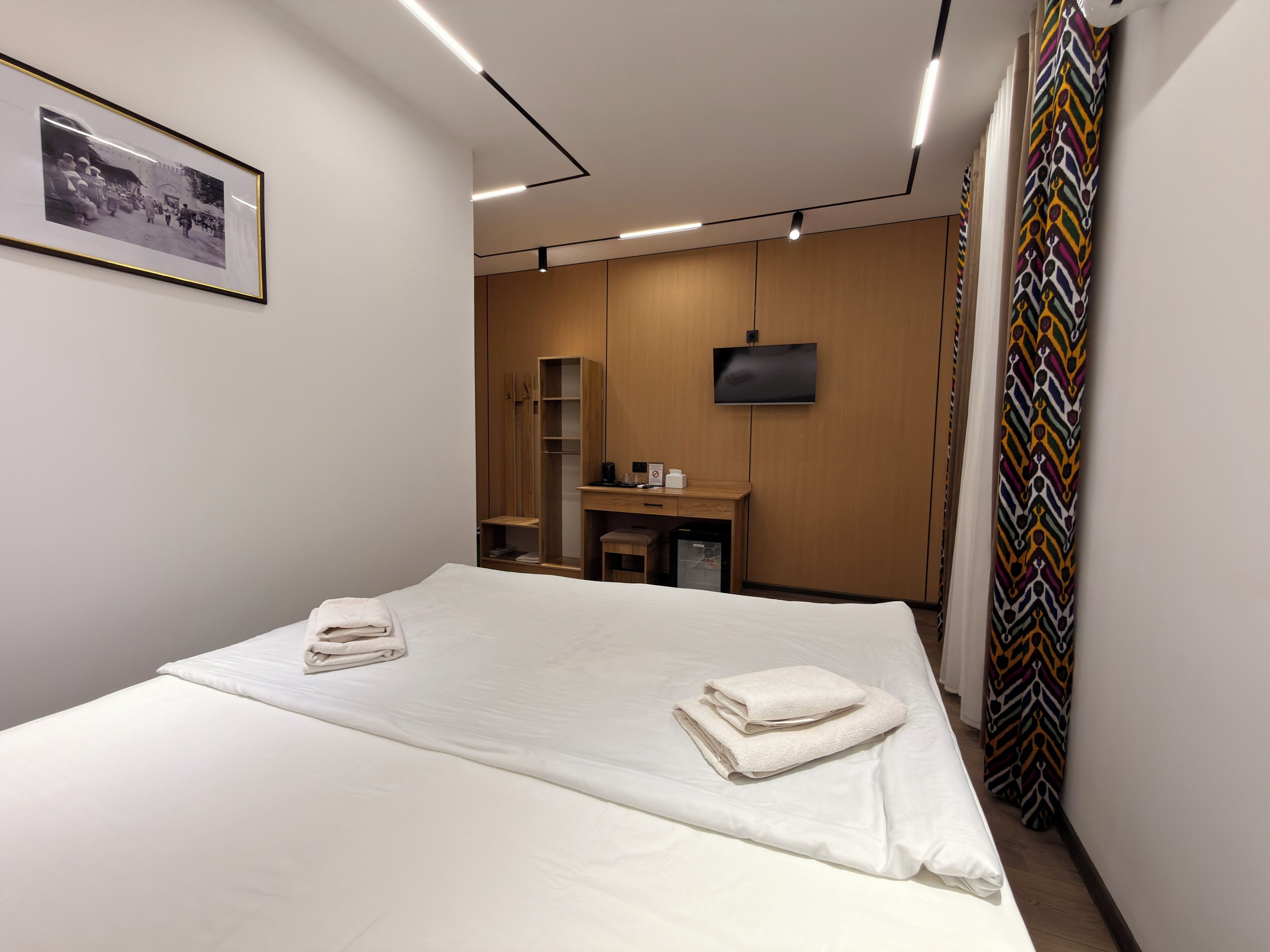 A hotel room with a bed, a desk, a television, and a wardrobe.