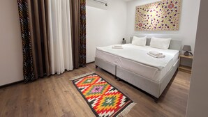 A modern bedroom with a large bed, a patterned rug, and a wall-mounted air conditioner. - Ulli Oy Boutique Hotel & Terrace (Khiva)