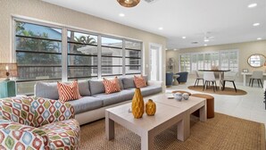 A spacious living room with a large sofa, a coffee table, and a dining area with a table and chairs.
