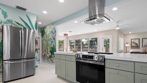 A modern kitchen with stainless steel appliances, a large island, and a decorative mural on the wall.