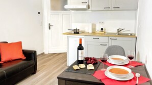 A compact kitchen with a dining table set for two, featuring a bottle of wine, two bowls of soup, and a plate of cheese. - Apartment in guter Lage zur Innenstadt (Dortmund)