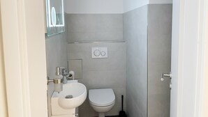 A small, modern bathroom with a white sink, toilet, and a mirror above the sink. - Apartment in guter Lage zur Innenstadt (Dortmund)