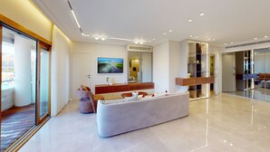 Un salon moderne avec un grand canapé blanc, une table basse en bois et un téléviseur à écran plat fixé au mur.