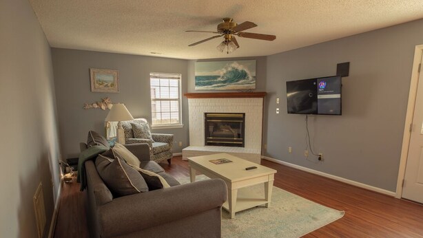 A living room with a sofa, armchair, fireplace, television, and ceiling fan. - A quiet lakeside home for family, business, or both to relax or be productive. (Virginia Beach)
