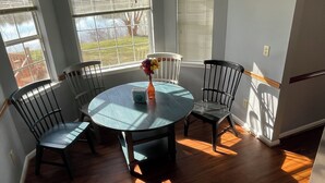 A dining area with a round table and four chairs, large windows with blinds, and a view of a yard. - A quiet lakeside home for family, business, or both to relax or be productive. (Virginia Beach)