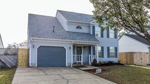 A two-story house with a garage, a front porch, and a small front yard. - A quiet lakeside home for family, business, or both to relax or be productive. (Virginia Beach)