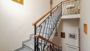 Un escalier avec une rampe en bois et des balustres en métal, menant à un palier où se trouvent une table et des chaises.