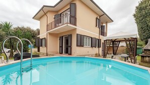 Une maison à deux étages avec une piscine, un patio couvert et un espace barbecue.