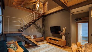 A spacious living area with a staircase, a television, a sofa, and a dining area. - Mater Hotel (Canela)