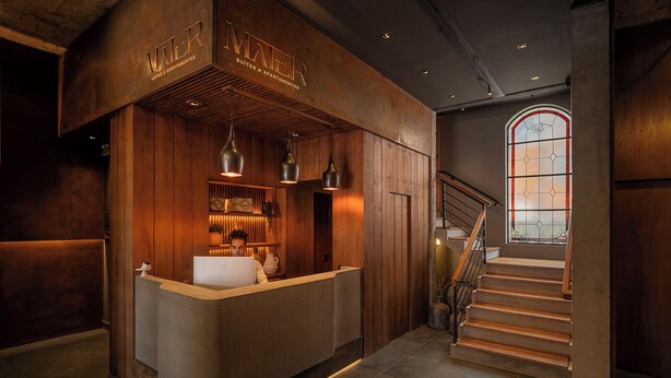 A reception desk with a wooden interior, a staircase, and a stained glass window. - Mater Hotel (Canela)