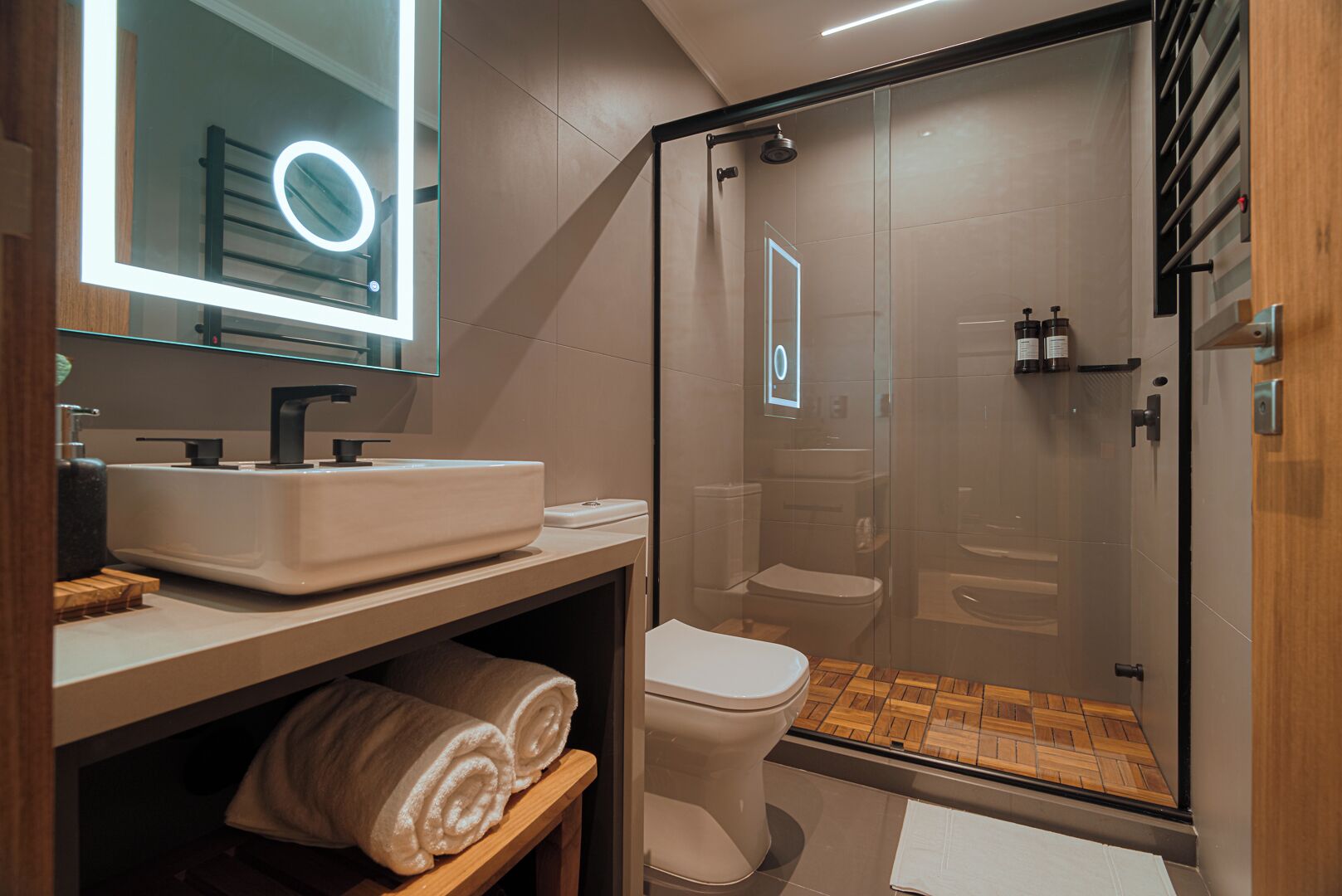 A modern bathroom with a glass-enclosed shower, a vanity with a large mirror, and a toilet.