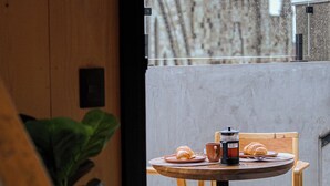 A round table with a coffee pot, a croissant, and a cup on a balcony with a view of a historic building. - Mater Hotel (Canela)