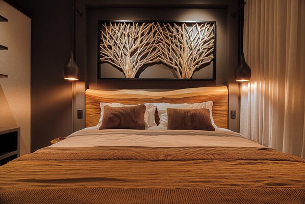 A modern hotel room with a large bed, a wooden headboard, two wall-mounted lamps, and a decorative tree artwork above the bed. - Mater Hotel (Canela)