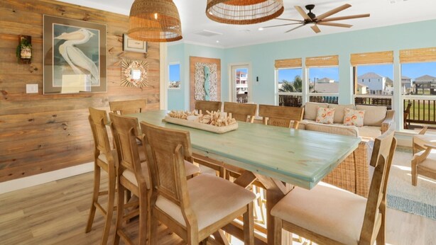 Un comedor con una mesa y sillas de madera, un ventilador de techo y vistas al exterior.
