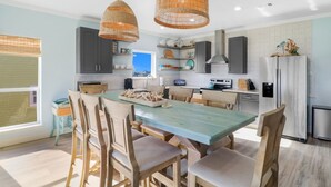 Una cocina moderna con una isla central, sillas de madera y una lámpara colgante.