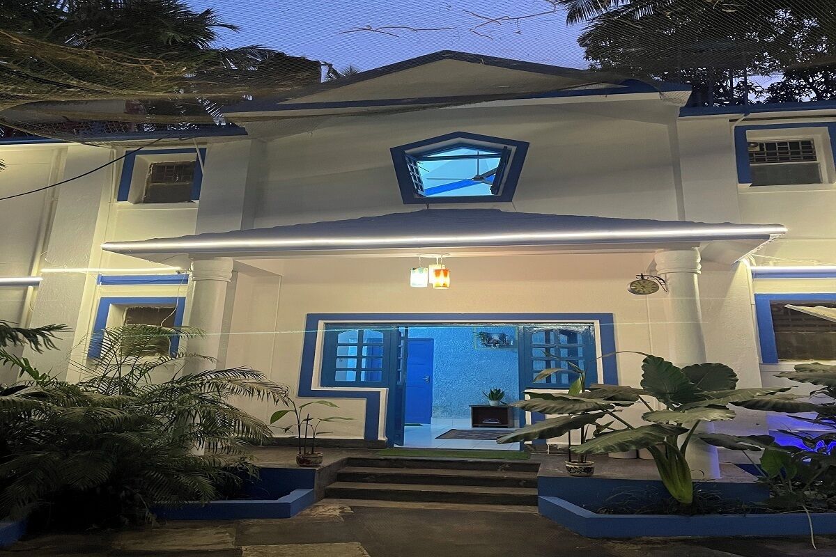 A two-story building with a central entrance, a small balcony, and a blue-framed door.