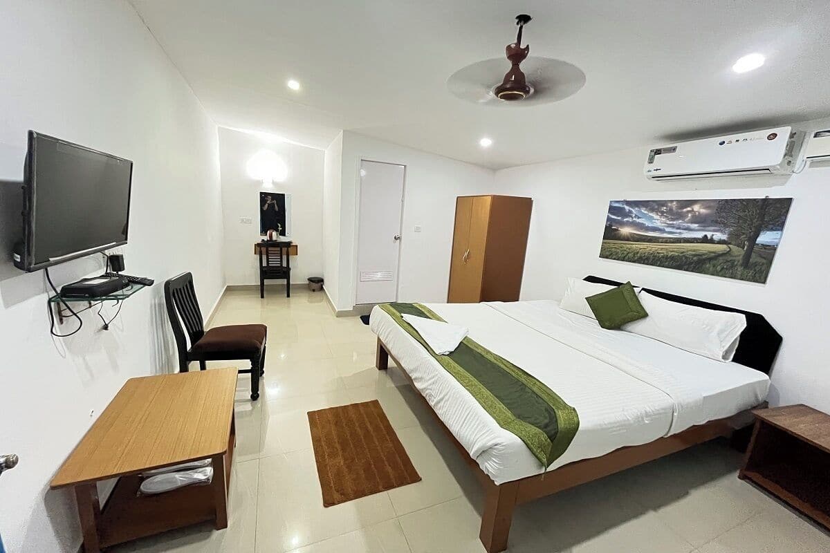 Une chambre d’hôtel équipée d’un lit, d’un bureau, d’une chaise, d’une armoire, d’un téléviseur et d’un appareil de climatisation.