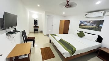 Habitación de hotel con cama, escritorio, silla, armario, televisor y aire acondicionado.