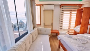 Una habitación de hotel con sofá, cama, armario de madera y una mesita.