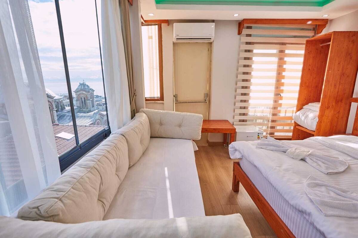 Een hotelkamer met een sofa, een bed, een houten garderobe en een klein tafeltje.